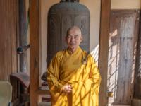 Mönch vor schmiedeeiserner Glocke im Tempel Vinh Trang - My Tho - Vietnam